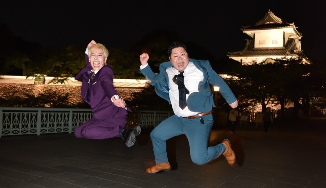 夜の金沢城を背景にジャンプする一夜城の二人
